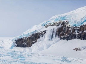 An avalanche cascades off a cliff at Athabasca Glacier in the Colombia Icefield.