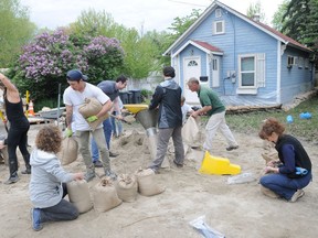 Volunteers and neighbours fill sandbags and sandbag around properties on Burne Avenue on Thursday afternoon. The City of Kelowna remains on high alert with possible damaging floods.