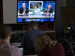 Reporters watch the British Columbia election leadership live radio debate with NDP Leader John Horgan, Liberal Leader Christy Clark and Green Party Leader Andrew Weaver on a television in Vancouver, Thursday, April 20, 2017.