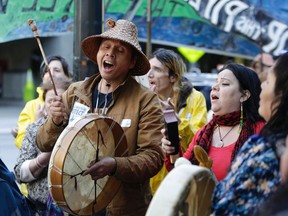 Paul Cheoketen Wagner, left, and Chelalakem Bond sing as indigenous leaders and climate activists disrupt business at a Chase Bank branch to protest funding tar sands development and projects like the Keystone XL pipeline, in Seattle, Washington on May 8, 2017.