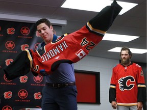 New Calgary Flames goalie Mike Smith, right watches as defenceman Travis Hamonic tries on his jersey after the two players were introduced at the Scotiabank Saddledome in Calgary on June 26, 2017.