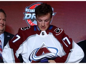 Cale Makar puts on the Colorado Avalanche jersey after being selected fourth overall during the 2017 NHL Draft at the United Center on June 23, 2017 in Chicago, Illinois.