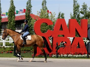 A rider passes by a Canada 150 sign at Spruce Meadows in Calgary.