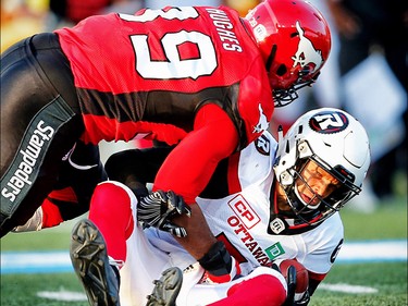 Ottawa Redblacks Trevor Harris is sacked by Charleston Hughes of the Calgary Stampeders during CFL football in Calgary. AL CHAREST/POSTMEDIA