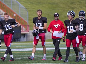 Calgary Stampeders quarterbacks from left; Andrew Buckley, Ricky Stanzi, Bo Levi Mitchell and Gale Mitchell walk off the field with quarterback coach Ryan Dinwiddie, centre, following practise at McMahon Stadium on June 15, 2017.