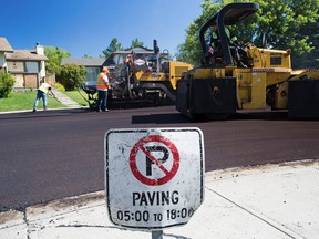 City of Calgary crews lay down asphalt along Woodford Drive in Woodbine on Tuesday June 27, 2017.