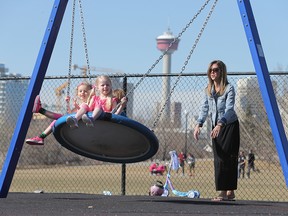 Heather Malsbury pushes her daughters Ava and  Kaylan, and friend Sacha Boridy on the swing at the community playground in Bridgeland.