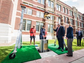 Jim Szautner (left), SAIT interim Dean of the School of Manufacturing and Automation, and Dr. David Ross, SAIT President and CEO, guide the SAIT time capsule into its final resting place as 102-year-old Clarence Hollingworth, SAIT’s oldest known alumnus, looks on. The time capsule will be opened in 2116.