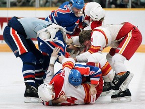 Dave Semenko, left, is in the middle of a classic Battle of Alberta brawl at the Saddledome on April 4, 1986. Flames Joel Otto and Jim Peplinski are also in the pile.