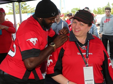 The Calgary Stampeders' Ja’Gared Davis signs the jersey of Yvonne Affleck outside McMahon Stadium before the team's home opener against the Ottawa Redblacks on June 29, 2017.  Gavin Young/Postmedia Network