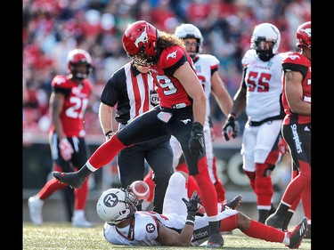 Calgary Stampeders Alex Singleton steps over Mossis Madu Jr. of the Ottawa Redblacks during CFL football in Calgary. AL CHAREST/POSTMEDIA