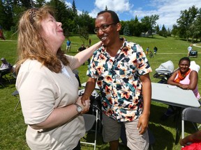 Neighbours Jodie Wiebe (L) and Daniel Asfeday shake hands and share a laugh during the Sunalta community's Neighbour Day event held in southwest Calgary on Saturday June 17, 2017. The pair were forced from their homes following a recent fire which leveled their apartment building and they joined others from the Sunalta Community Association at the event held at Royal Sunalta Park, a couple blocks from the fire scene. Jim Wells//Postmedia