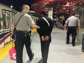Calgary Transit safety officers Brian Meanley, left, and Mathieu Young take a man into custody at the Erlton Stampede LRT station. Bryan Passifiume/Postmedia Network