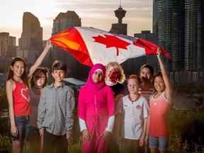 Kids from left, Taylor Sim, 12, Leah Tuck, 10, Alif Jamal,10, Diana Al Kawairt,11, Remco Van Dijk, 10, Joel Newmarch, 10, Yara Issa,11, and Parker Sim, 9, wave the flag on top of Scotsman's Hill in Calgary on Thursday June 29, 2017. Leah Hennel/Postmedia