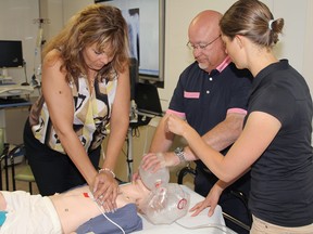 Diana Wennerstrom, from left, and Peter MacIntyre with the Willow Park Charity Golf Classic, try performing CPR on a high-tech mannequin with Jenny Chatfield with the Alberta Children's Hospital's KidSIM team.