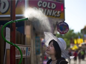 Anqi Liu tries to keep cool as temperatures soar during Sneak-a-Peek at the Calgary Stampede on Thursday July 6, 2017. Leah Hennel/Postmedia

Stampede2017
Leah Hennel, Leah Hennel/Postmedia