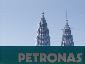 A Petronas gas station signage is pictured against Malaysia's landmark building, Petronas Twin Towers in Kuala Lumpur, Malaysia, Wednesday, March 2, 2016. National oil company Petroliam Nasional Bhd (Petronas) Tuesday, announced a layoff of almost 1,000 staff.