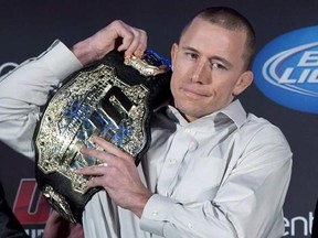 Welterweight UFC champion Georges St-Pierre put his belt on his shoulder during a news conference in Montreal on January 23, 2013. The UFC has decided against matching St-Pierre with current title-holder Tyron (The Chosen One) Woodley, opting instead to return to its original plan and have the Canadian star make his comeback against middleweight champion Michael Bisping.THE CANADIAN PRESS/Paul Chiasson
