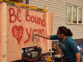 Marie-Lise Landry spray-paints a message on a supply trailer bound for B.C. firefighters, in Fort McMurray, Alta.