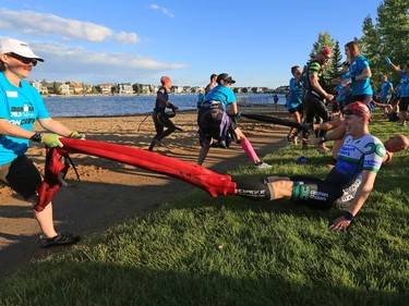 Volunteers help competitors get out of their wet suits after finishing the swim portion of the Calgary Ironman 70.3 race at Auburn Lake on Sunday July 23, 2017.