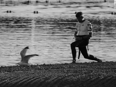 A competitor stretches at the on the beach at Auburn Lake before the start of the Calgary Ironman 70.3 race on Sunday July 23, 2017.