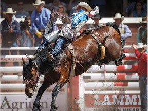 J.R. Vezain, from Cowley, Wyoming, stays on You See Me during bareback rodeo action at the Calgary Stampede in Calgary, Alta., Saturday, July 8, 2017.