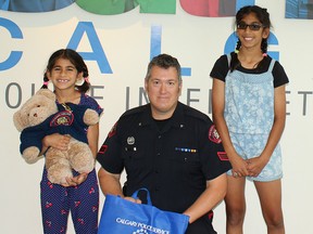 Sisters Ashlynn (left) and Jasmine Walia pose with Sgt. Paul Dunn, who went out of his way to replace Ashlyn's teddy bear she lost at this year's Calgary Stampede.