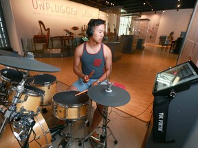 Sailin Li tries a drum lesson using video instruction in the 'Unplugged' exhibit at the National Music Centre in Calgary on Saturday July 15, 2017. the City of Calgary is looking at giving 10 cornerstone art agencies an extra $2 million this year, about double their normal contribution, to help them weather the financial storm. Jim Wells/Postmedia