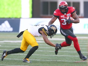 Stamps running back Jerome Messam (R) is tackled by Khalid Wooten (L) during CFL action between the Hamilton Tiger Cats and the Calgary Stampeders in Calgary at McMahon Stadium Saturday, July 29, 2017. Jim Wells/Postmedia