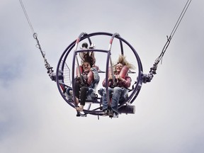 Postmedia reporter Alanna Smith rides the Slingshot ride with Calgary Stampede midway rep Allison Wright. The ride is one of the most extreme on the grounds this year and sends thrill-seekers hurtling 300 feet in the air at 100 km/h  KERIANNE SPROULE/POSTMEDIA