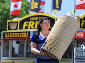 Lammle's Western Wear & Tack manager Stefania Mounsey carries a stack of cowboy hats as she sets up the company's store on the Calgary Stampede midway on Monday July 3, 2017. GAVIN YOUNG/POSTMEDIA
