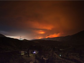 A wildfire burns on a mountain in the distance east of Cache Creek behind a trailer park that was almost completely destroyed by wildfire, in Boston Flats, B.C., in the early morning hours of Monday July 10, 2017.