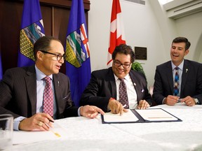 Alberta Finance Minister Joe Ceci, left, Calgary Mayor Naheed Nenshi, centre, and Edmonton Mayor Don Iveson sign a new city charter at the Alberta Legislature Building in Edmonton on Aug. 10, 2017.