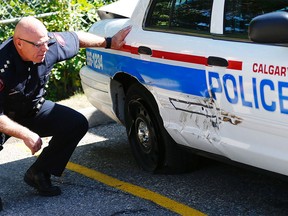 Acting Insp. Darren Cave checks out the damage on a police cruiser that was rammed by a stolen truck on Monday, Aug. 21, 2017.