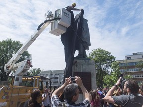 A Halifax City staff member covers the Edward Cornwallis statue with a black tarp as activists protest in Cornwallis Park in Halifax on Saturday, July 15, 2017. Protesters who pledged to remove a statue of Halifax's controversial founder Saturday say they came away victorious after the monument to Edward Cornwallis was covered in a tarp. THE CANADIAN PRESS/Darren Calabrese