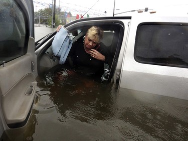 Rhonda Worthington talks on her cell phone with a 911 dispatcher as he gets out of her car after her vehicle become stalled in rising floodwaters from Tropical Storm Harvey in Houston, Texas, Monday, Aug. 28, 2017. Worthington said she thought the water was low enough to drive through before the vehicle started to float away. (AP Photo/LM Otero) ORG XMIT: TXMO105