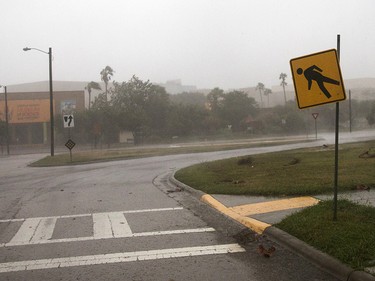 A pedestrian crossing sign remains in place by one screw as Hurricane Harvey makes landfall in Corpus Christi, Texas, on Friday, Aug. 25, 2017. Hurricane Harvey smashed into Texas late Friday, lashing a wide swath of the Gulf Coast with strong winds and torrential rain from the fiercest hurricane to hit the U.S. in more than a decade.  (Nick Wagner/Austin American-Statesman via AP) ORG XMIT: TXAUS107