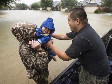 Wilfredo Linares reaches out for his baby, Mason, as they are evacuated from Grand Mission subdivision, as the water rises from heavy rains from Tropical Storm Harvey on Monday, Aug. 28, 2017, in Fort Bend County, Texas. (Brett Coomer/Houston Chronicle via AP) ORG XMIT: TXHOU101