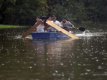 People use plywood to row a boat down Deats Road in Dickinson, Texas, Monday, Aug. 28, 2017, as floodwaters from Tropical Storm Harvey rise. (Kelsey Walling/The Galveston County Daily News via AP) ORG XMIT: TXGAL801