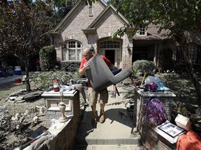Edward Casanova carries a chair as he helps dry out items from a friend's house after floodwaters from Harvey drenched the city Thursday, Aug. 31, 2017, in Houston.