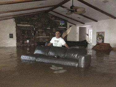 This Sunday, Aug. 27, 2017, photo provided by Ramit Plushnick-Masti, shows her husband, Rafi, standing in waist-high water inside their flooded home in Houston's Meyerland neighborhood that was caused by Tropical Storm Harvey. Plushnick-Masti and her family intended to ride out the storm in their Houston home, but their plan changed when the floodwaters rose over the weekend. (Ramit Plushnick-Masti via AP) ORG XMIT: CER105