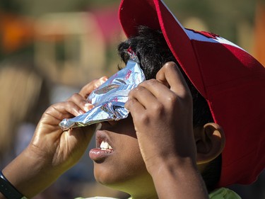 A boy uses a foil wrapper to view a partial solar eclipse from the Spark Science Centre in Calgary, Alta., Monday, Aug. 21, 2017.