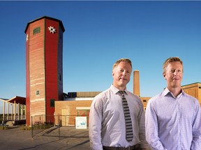Twin brothers Denis and Pat Willem, in front of the water tower and original carpenter's shop at St. Mary's University, where their company, Wii Projects, has worked on several projects.