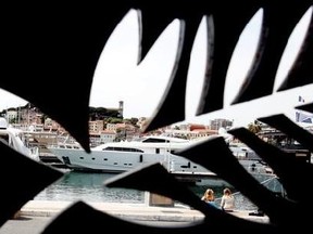 FILE - In this Tuesday, May 10, 2011, file photo, a yacht is seen behind a logo for the 64th international film festival, in Cannes, southern France. After a backlash over programming Netflix films, the Cannes Film Festival said it will, beginning next year, only accept theatrically released films for its prestigious Palme d‚ÄôOr competition. In a statement Wednesday, May 10, 2017, the French festival said it has adapted its rule to require films in competition to be distributed in French movie
