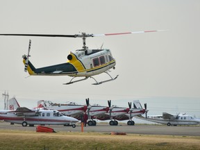 A helicopter lifts off as a number of fire suppression aircraft stand ready at the Pincher Creek firebase on Sunday. Bryan Passifiume/Postmedia Network