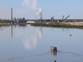 Syncrude workers in a recovery boat patrol a tailings pond north of Fort McMurray Alta. on Friday June 19, 2015.