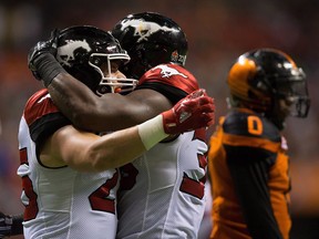 Calgary Stampeders' Rob Cote, left, and Jerome Messam celebrate Messam's touchdown as B.C. Lions' Loucheiz Purifoy, back right, walks to the sideline during the second half of a CFL football game in Vancouver on August 18, 2017. The Calgary Stampeders will look to run their winning streak to five straight games when they host the Toronto Argonauts at McMahon Stadium on Saturday night. THE CANADIAN PRESS/Darryl Dyck ORG XMIT: CPT117