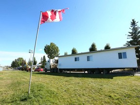 A tattered Canadian flag flaps in the wind as movers prep a double-wide trailer for a move at the Midfield Trailer Park.