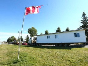 A tattered Canadian flag flaps in the wind as movers prepare to remove a unit from Midfield Trailer Park.