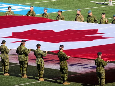 Soldiers carry a huge Canadian Flag during military appreciation day at the Labour Day Classic at McMahon Stadium, Monday September 4, 2017. Gavin Young/Postmedia